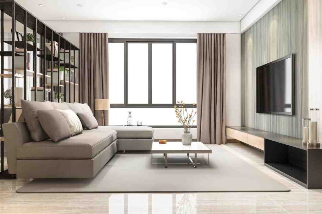 Modern living room featuring a gray sectional sofa, minimalist decor, large windows, and a sleek TV unit with natural light.