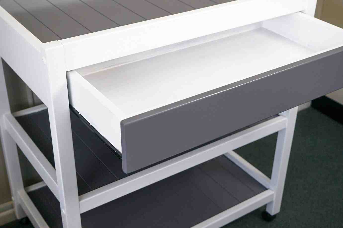 A close-up of a modern white and gray furniture piece showcasing an open drawer on a multi-tiered shelf unit.